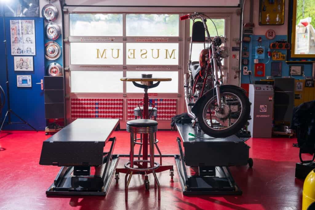 Schwarz-rote Motorrad auf Werkbank in stylischer Garage mit Werkzeugen und Kunstwerken.