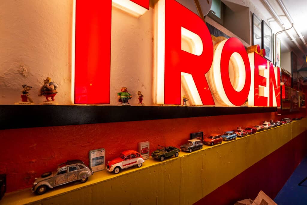 Lichterbuchstabe "ROEN" mit nostalgischen Autos und Figuren, stilvoller Blickfang im Altbau-Charme.