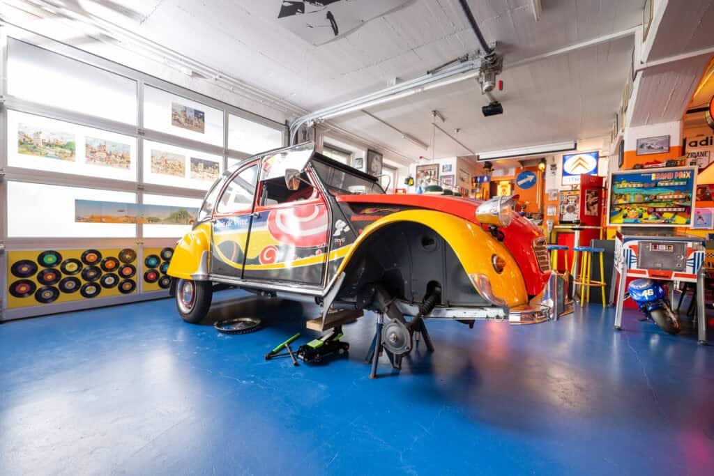 Bunter Citroën 2CV im Vintage-Garage Ambiente mit Figuren und Spielzeug.