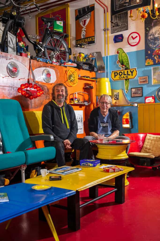 Bunte Garage mit Motorrädern, Kunstwerken und Vintage-Objekten im Hintergrund.